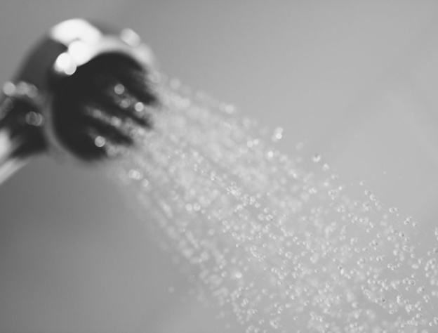 Close up lifestyle image of water spraying from a handset shower head